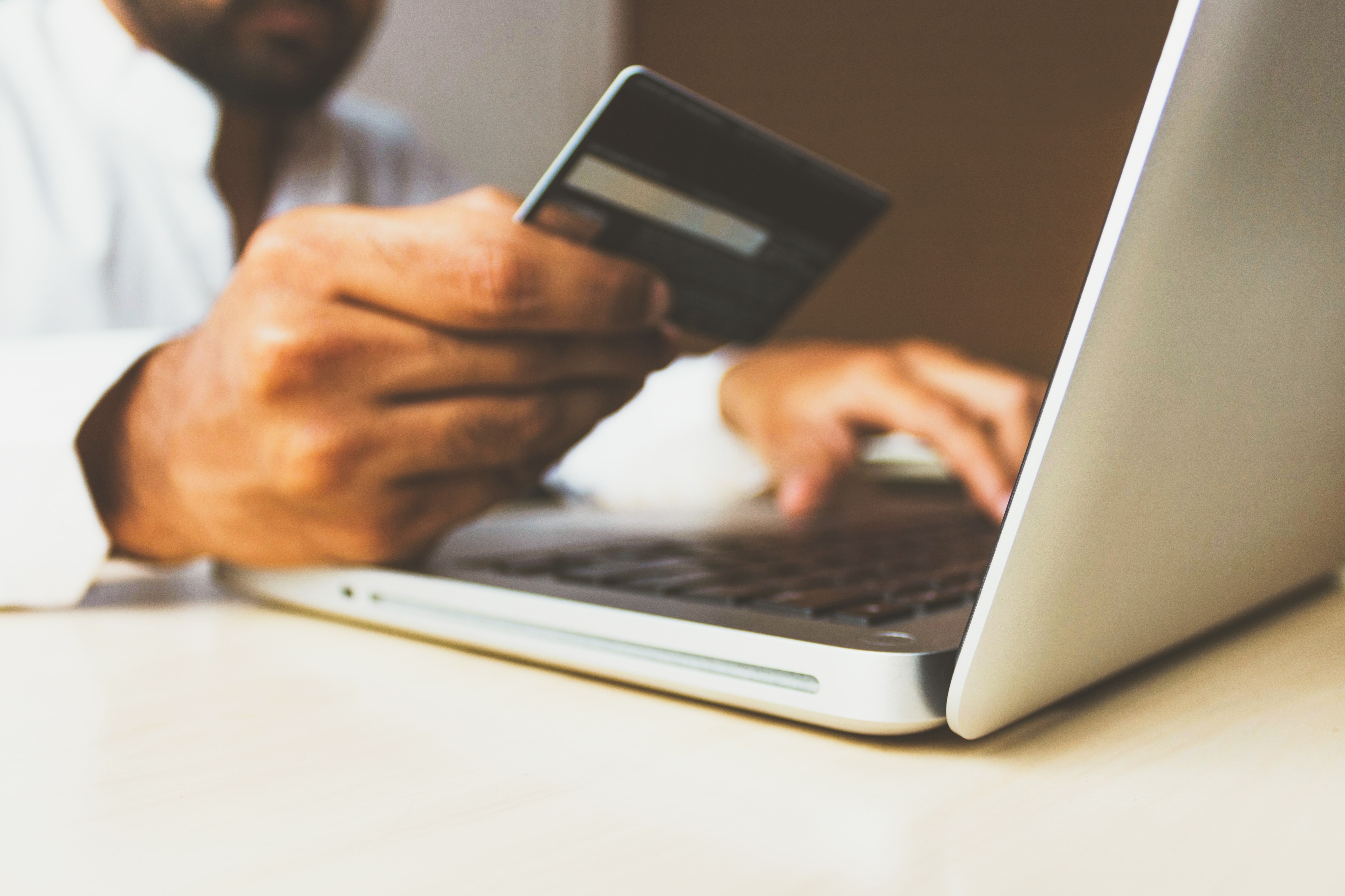 man-holding-a-card-in-front-of-a-laptop