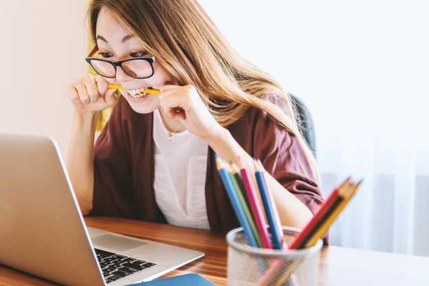 woman-biting-pencil-in-front-of-macbook