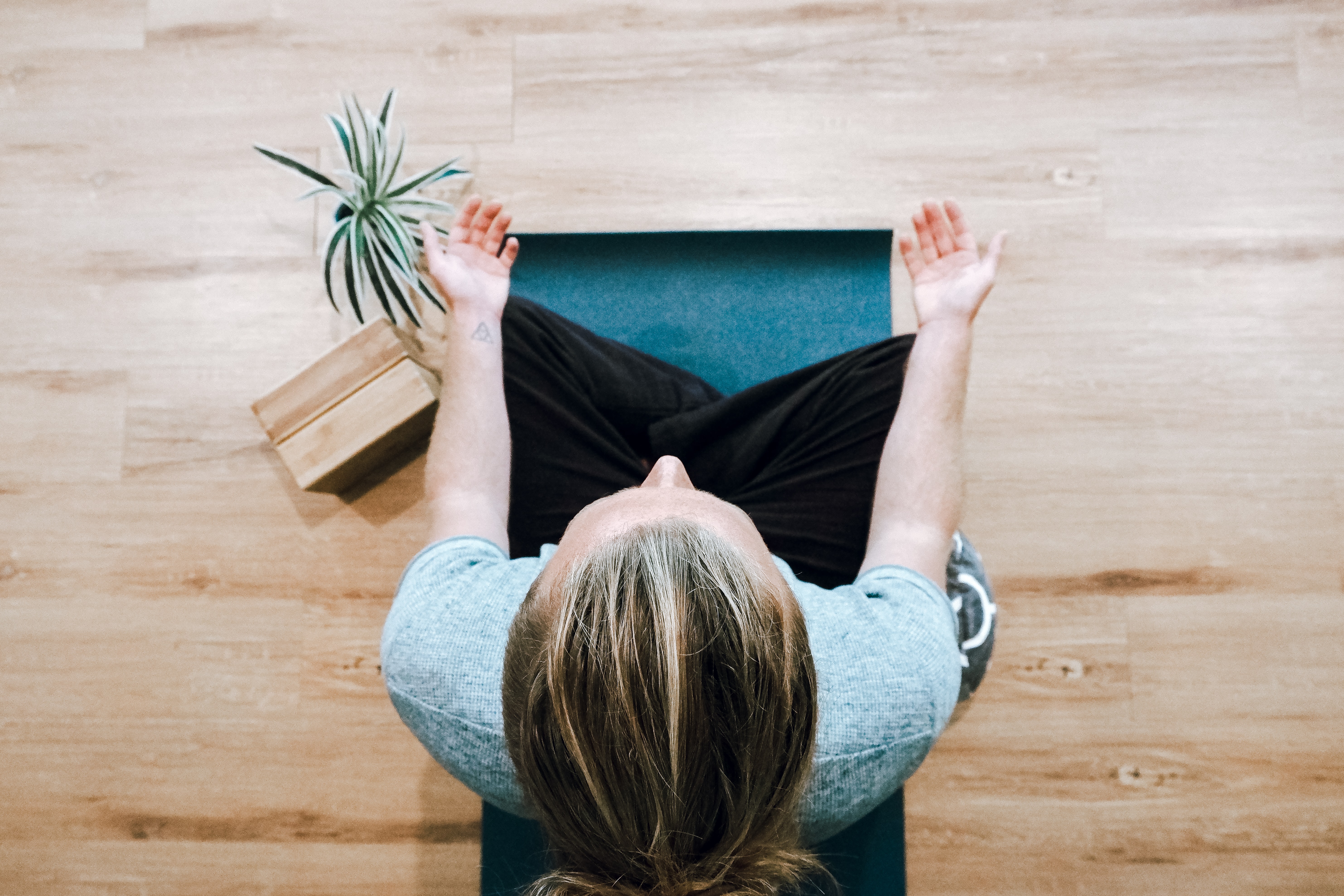woman-in-black-pants-and-gray-shirt-sitting-in-a-wooden-floor